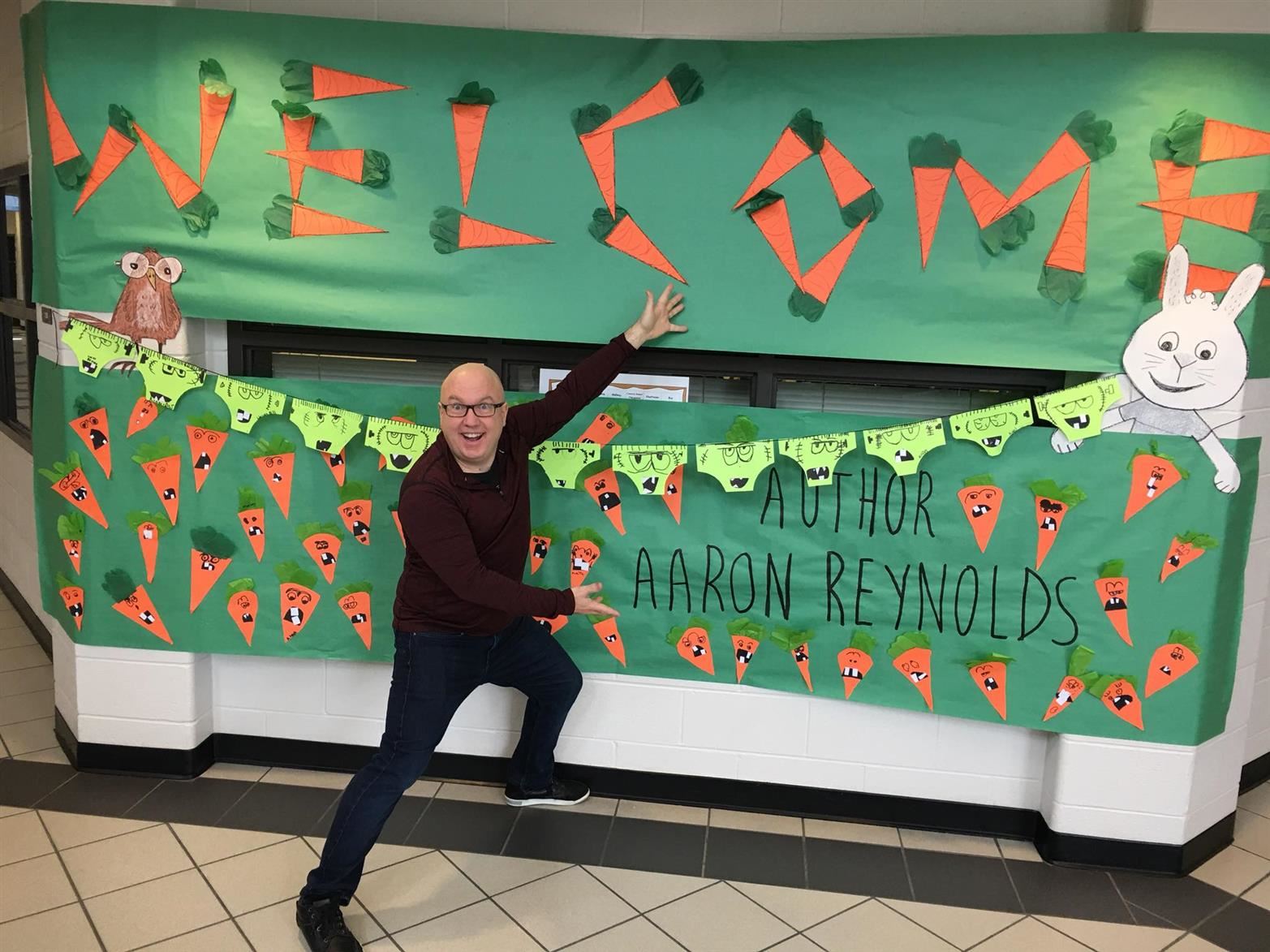 Aaron Reynolds posing with his welcome sign 